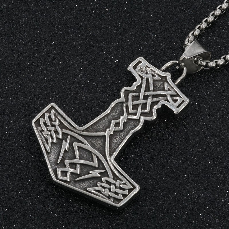 Silver pendant shaped like a bottle with intricate designs on a black background