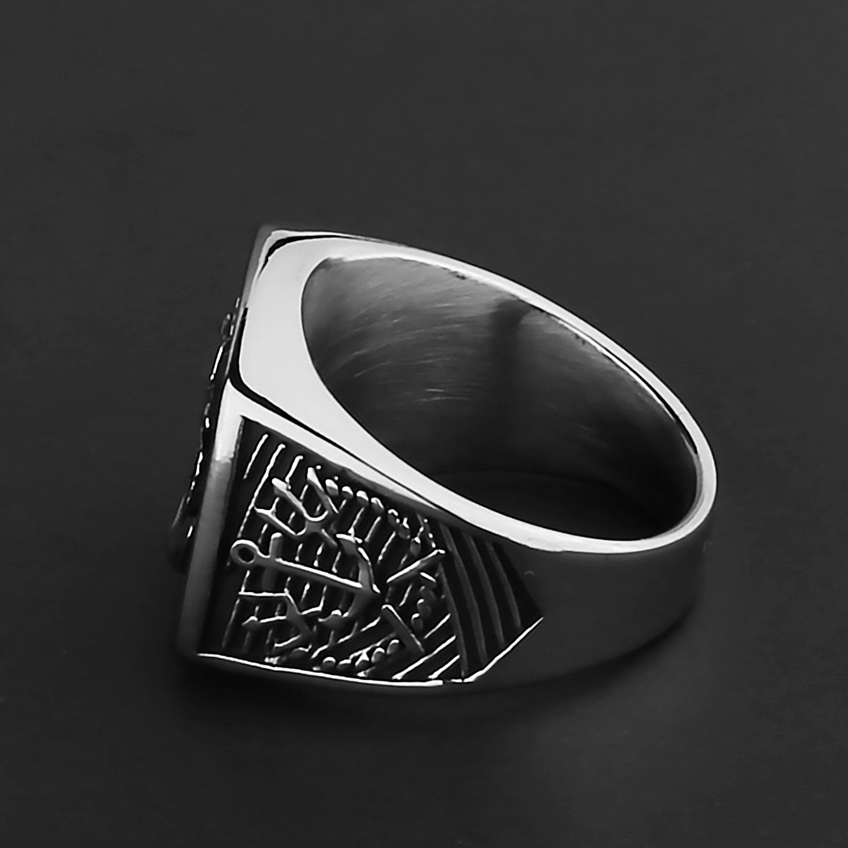 Silver ring with intricate design on a black background