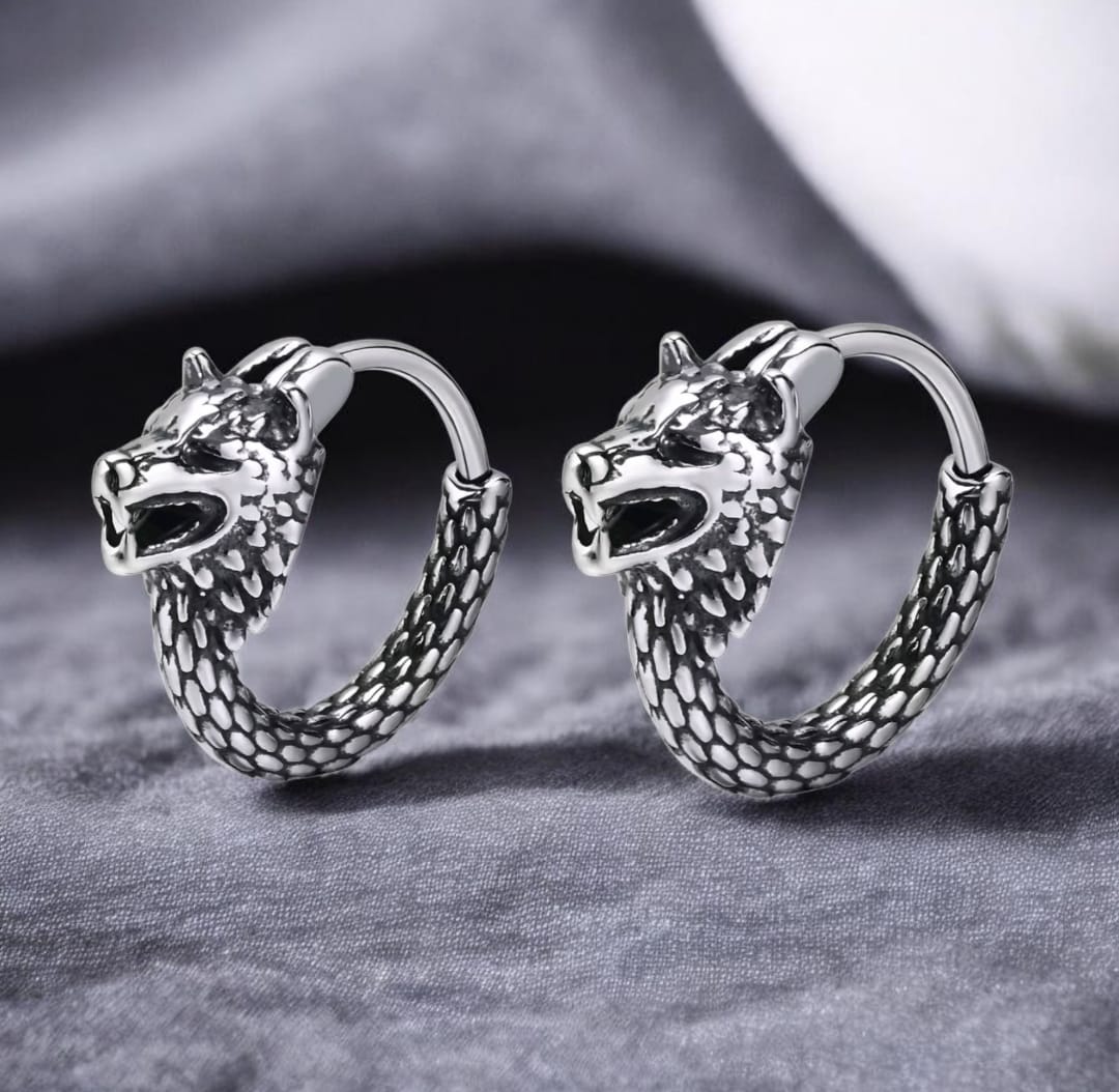 Pair of silver hoop earrings with wolf head design on a gray fabric background