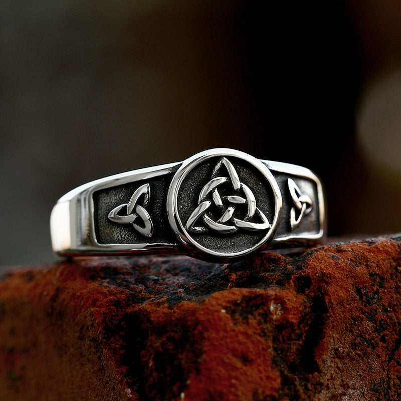 Silver ring with Celtic knot design on a textured surface
