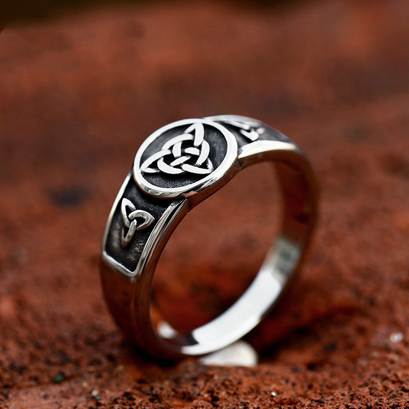 Silver ring with Celtic knot design on a brown textured background
