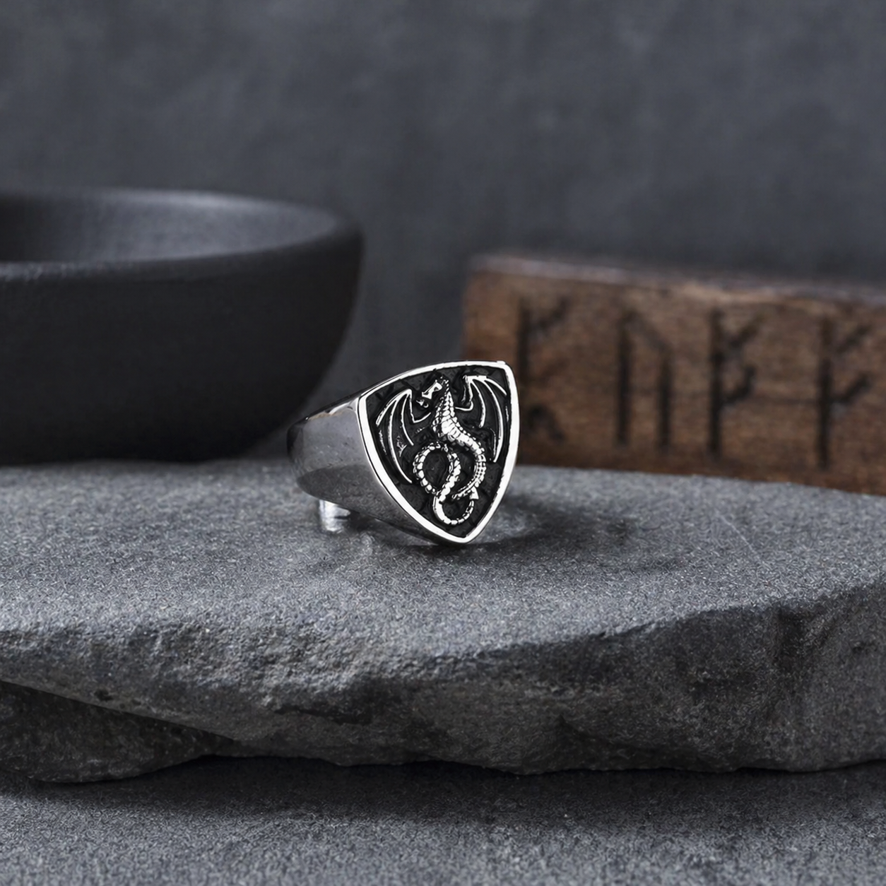 Silver ring with a dragon design on a stone surface