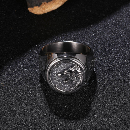Silver ring with dragon emblem on a black textured surface