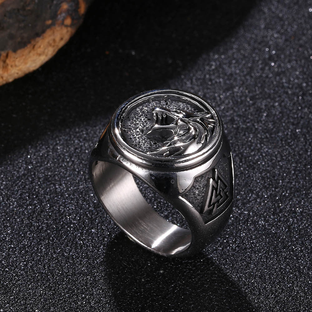 Silver ring with engraved design on a dark textured surface