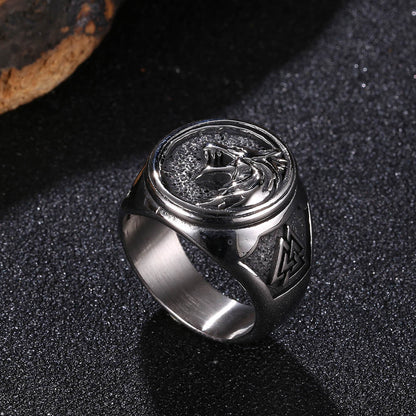 Silver ring with engraved design on a dark textured surface