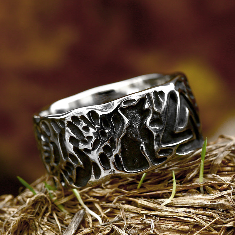 Silver ring with intricate design on a grassy surface
