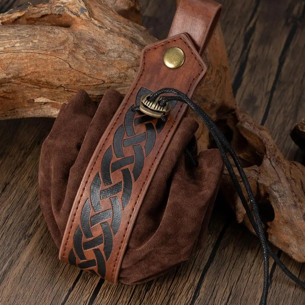 Brown leather pouch with braided design and gold button on a wooden surface