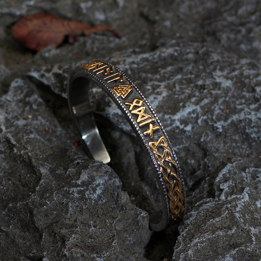 Silver and gold bracelet withRunes on a stone surface
