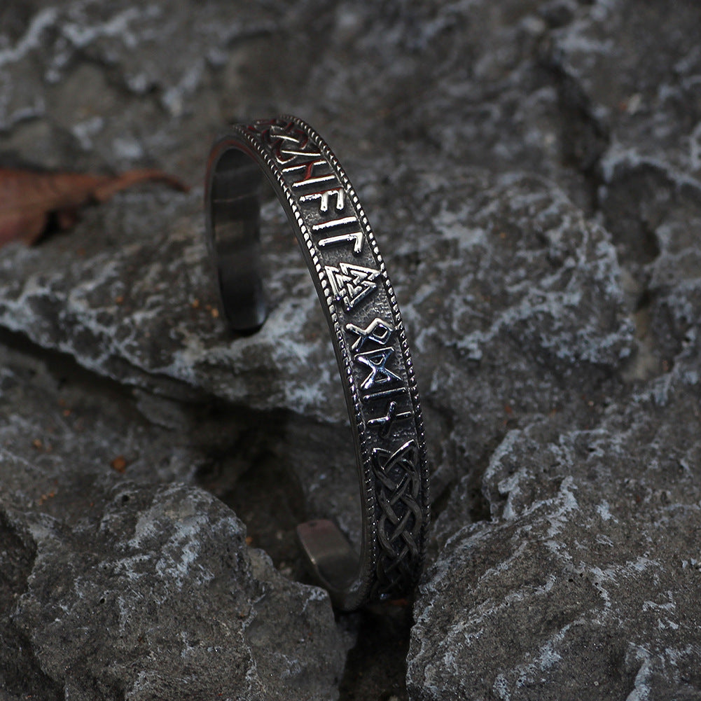 Silver bracelet with engraved text on a stone surface