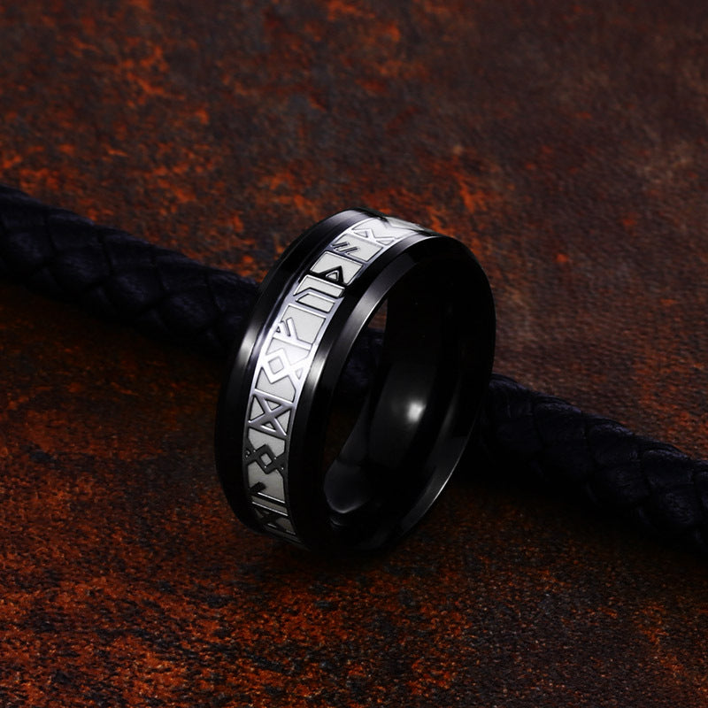 Black ring with silver pattern on a textured brown surface
