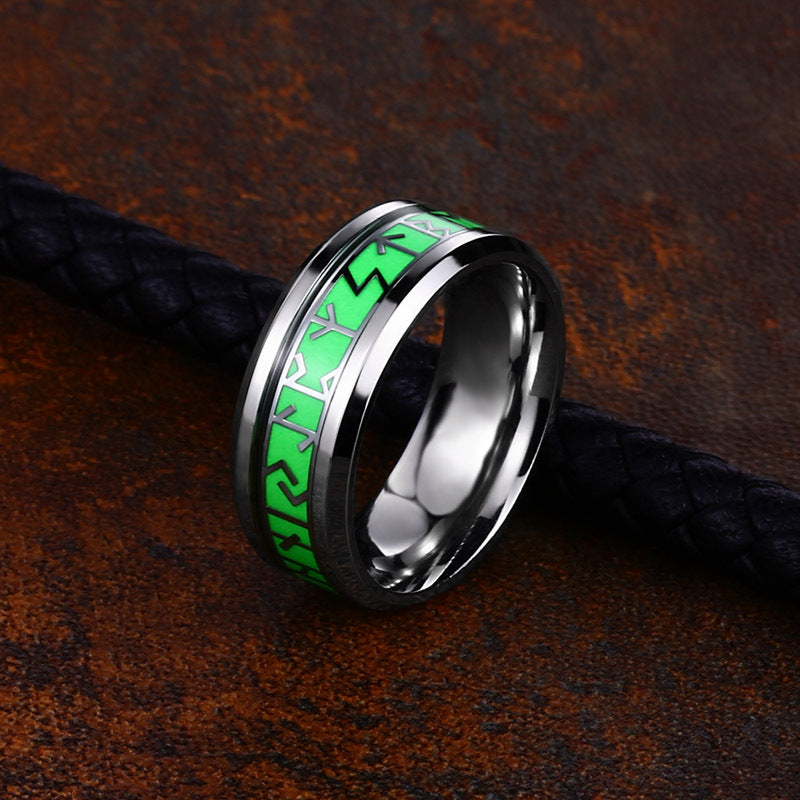 Silver ring with green inlay on a textured brown surface
