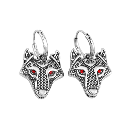 A pair of silver-toned wolf head hoop earrings with textured detailing and small red gemstone eyes, shown on a plain white background.